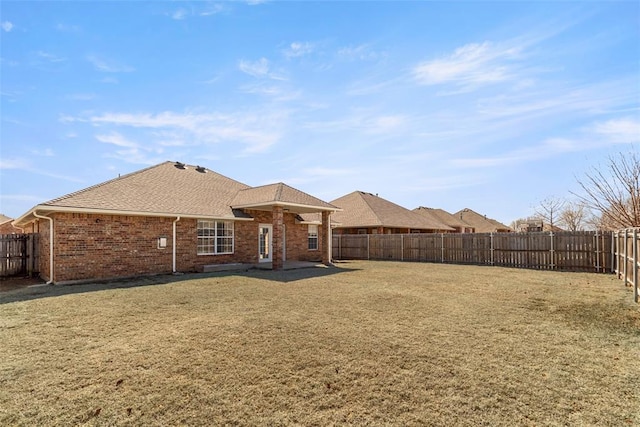 back of property featuring a lawn, brick siding, and a fenced backyard