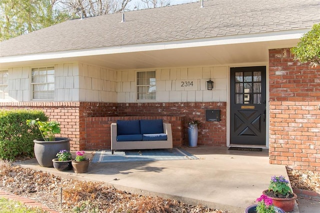 property entrance featuring brick siding and roof with shingles