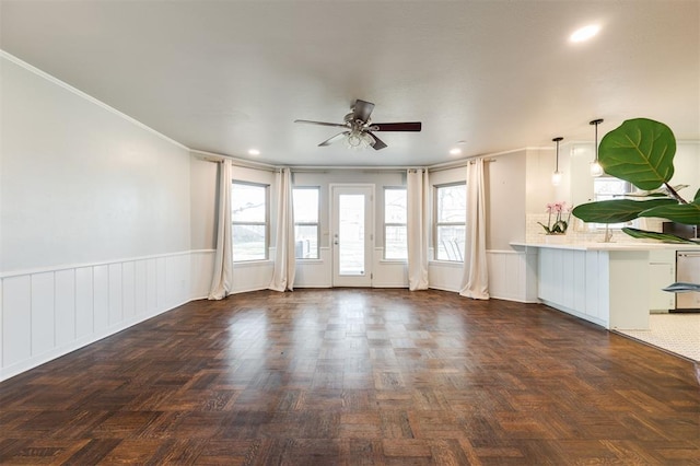 unfurnished living room with recessed lighting, wainscoting, a ceiling fan, and ornamental molding