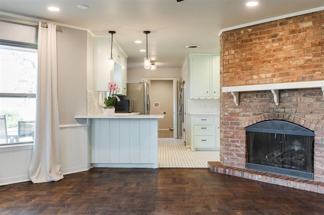 kitchen featuring a wealth of natural light, a peninsula, stainless steel refrigerator with ice dispenser, and light countertops