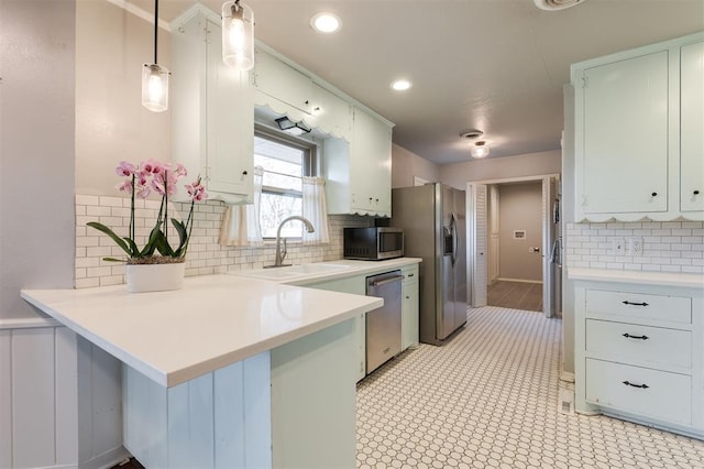 kitchen with a peninsula, pendant lighting, light countertops, and stainless steel appliances