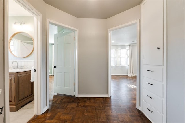 corridor featuring baseboards and a sink