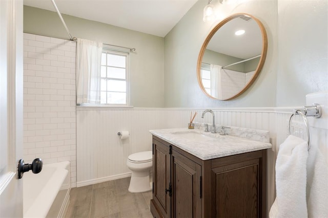 full bath with a wainscoted wall, toilet, wood finished floors, vanity, and shower / bathtub combination with curtain