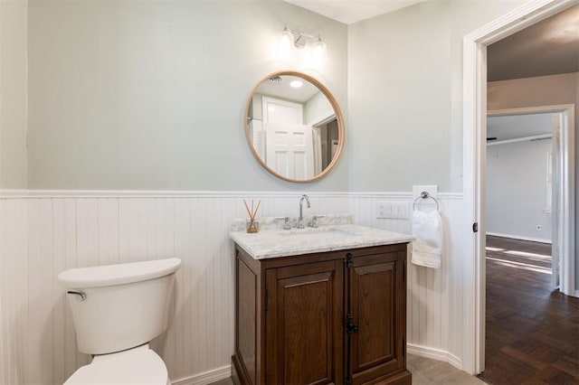 bathroom featuring vanity, wainscoting, and toilet