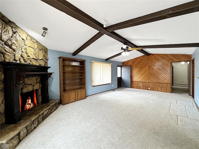 carpeted living room with ceiling fan, wooden walls, a fireplace, and vaulted ceiling with beams