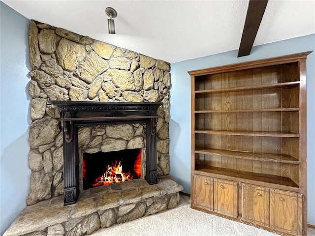 room details featuring carpet floors, a textured ceiling, and a stone fireplace