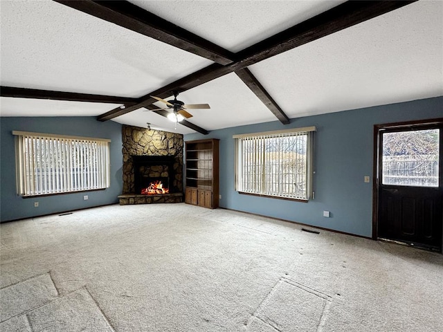 unfurnished living room featuring visible vents, a textured ceiling, a stone fireplace, carpet flooring, and vaulted ceiling with beams