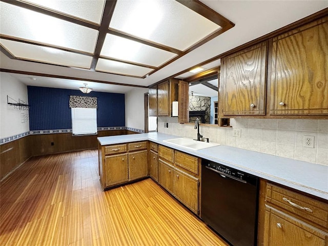 kitchen with a wainscoted wall, a sink, light countertops, dishwasher, and light wood-type flooring