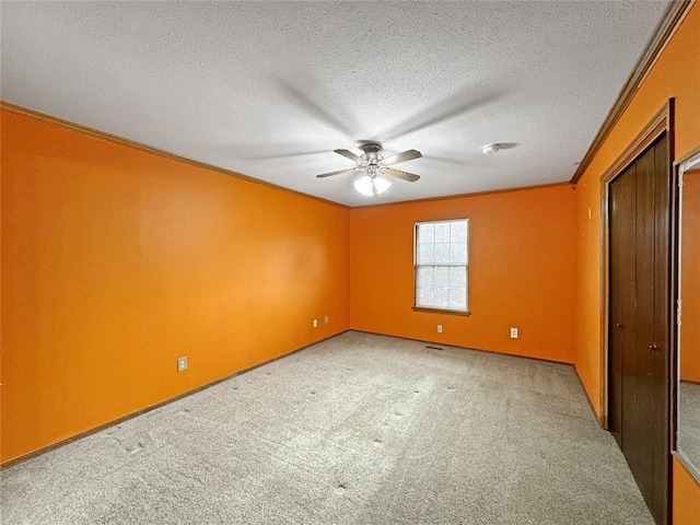 unfurnished bedroom featuring a ceiling fan, a textured ceiling, ornamental molding, and carpet flooring