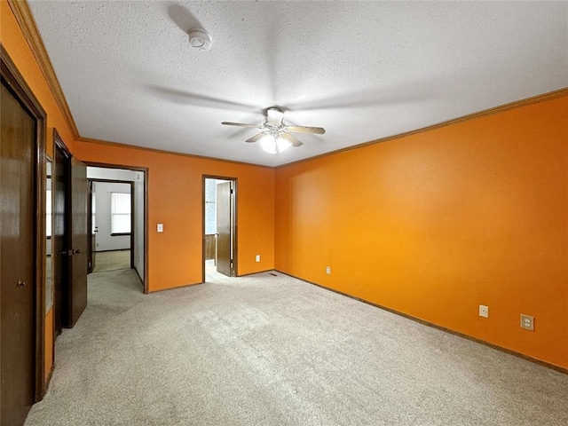 unfurnished bedroom featuring baseboards, light carpet, a textured ceiling, and ornamental molding