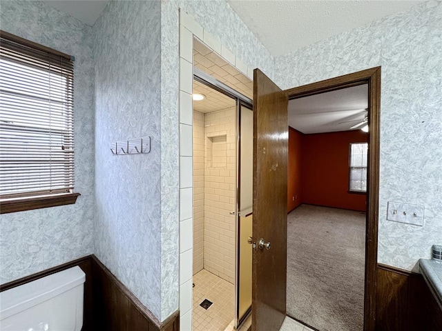 full bathroom with a wainscoted wall, toilet, and wallpapered walls