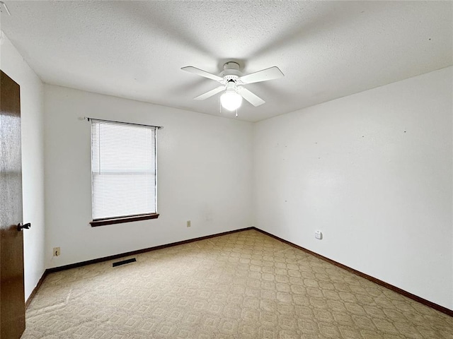 empty room featuring visible vents, ceiling fan, a textured ceiling, and baseboards