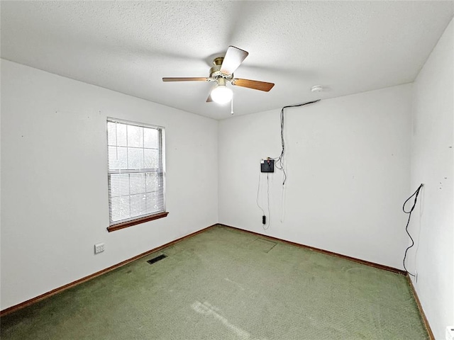 carpeted empty room with visible vents, ceiling fan, a textured ceiling, and baseboards