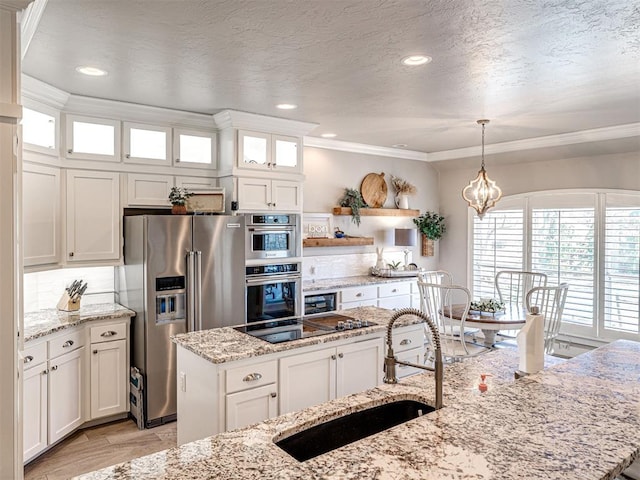 kitchen with a sink, a center island, white cabinetry, appliances with stainless steel finishes, and crown molding