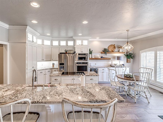 kitchen with a sink, white cabinets, a kitchen island, and stainless steel appliances