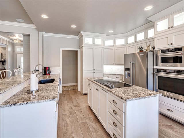 kitchen with a sink, stainless steel appliances, light stone counters, and a peninsula