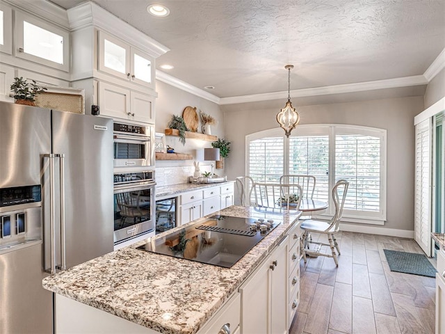 kitchen with a textured ceiling, a center island, stainless steel appliances, white cabinets, and crown molding