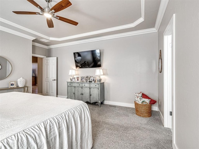 carpeted bedroom with a tray ceiling, baseboards, ceiling fan, and crown molding