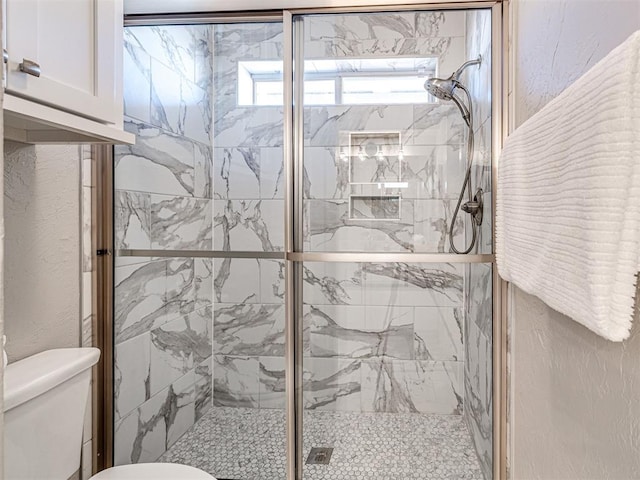 bathroom featuring a shower stall, toilet, and a textured wall