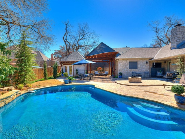 view of pool featuring an exterior structure, a fenced in pool, fence, a patio area, and an outbuilding