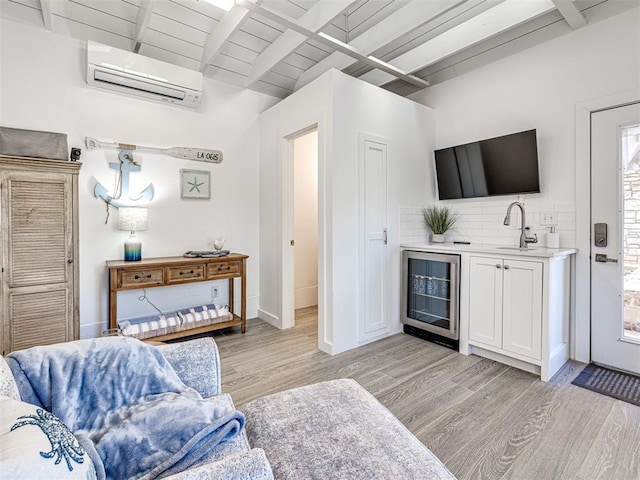 living room with baseboards, a wall mounted AC, lofted ceiling with beams, wine cooler, and light wood-type flooring