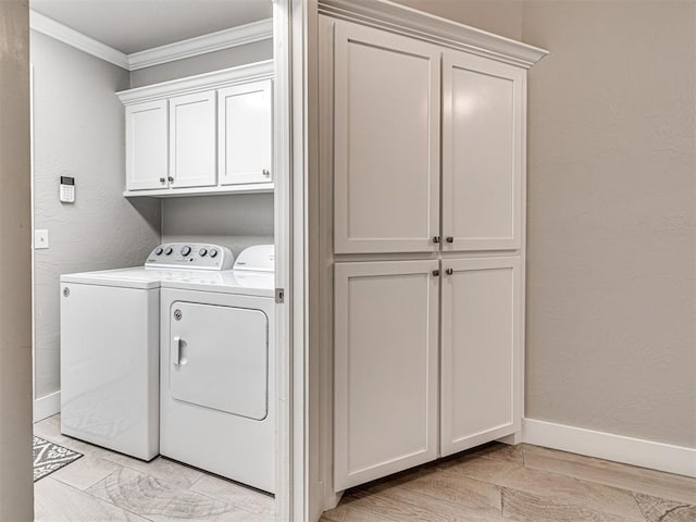 washroom with baseboards, cabinet space, separate washer and dryer, ornamental molding, and a textured wall