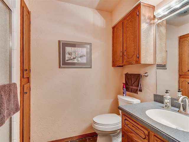 bathroom featuring vanity, toilet, and a textured wall