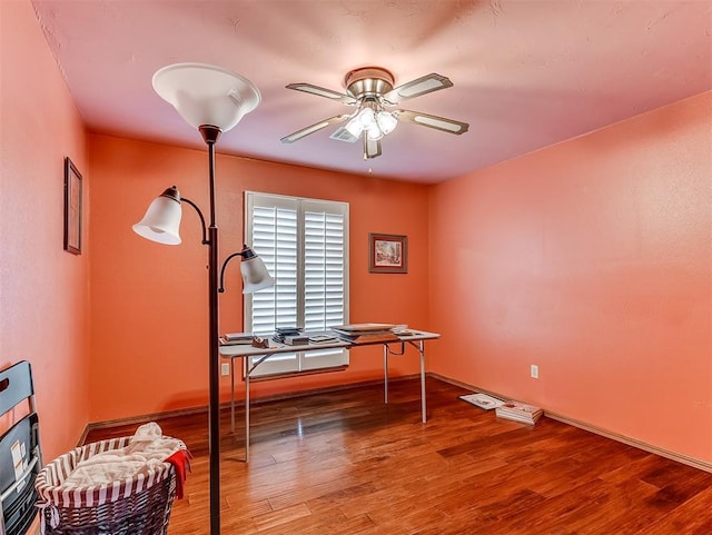 misc room with baseboards, ceiling fan, and wood finished floors