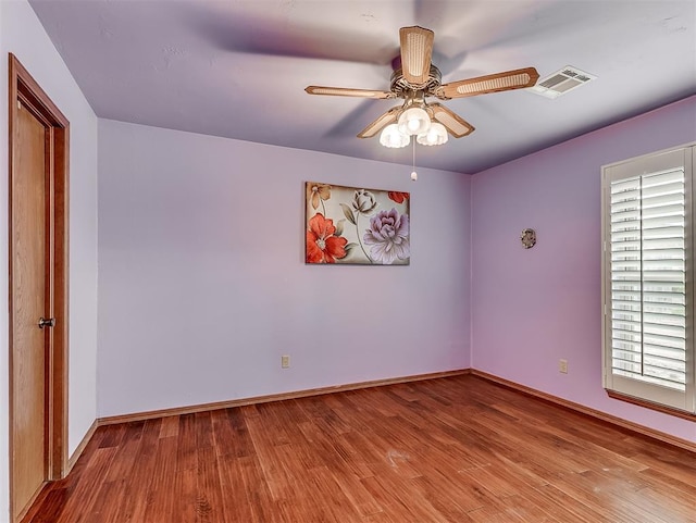 spare room featuring visible vents, wood finished floors, baseboards, and ceiling fan