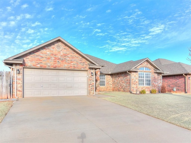 single story home featuring a front yard, driveway, roof with shingles, an attached garage, and brick siding