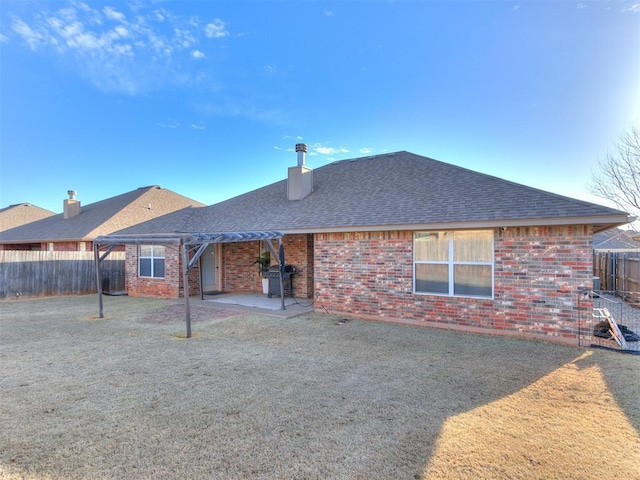 rear view of house with brick siding, a fenced backyard, a patio area, and roof with shingles