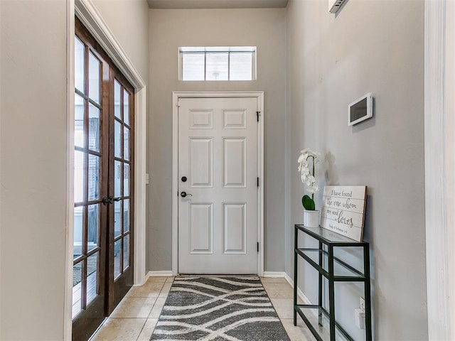 foyer entrance featuring light tile patterned flooring, french doors, and baseboards