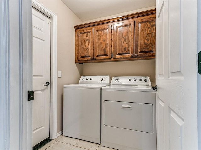 laundry room featuring cabinet space, light tile patterned flooring, and washing machine and clothes dryer