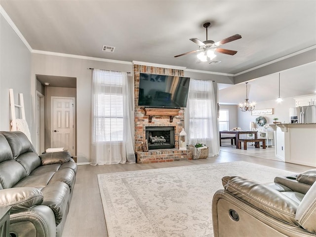 living area with plenty of natural light, a brick fireplace, visible vents, and ornamental molding