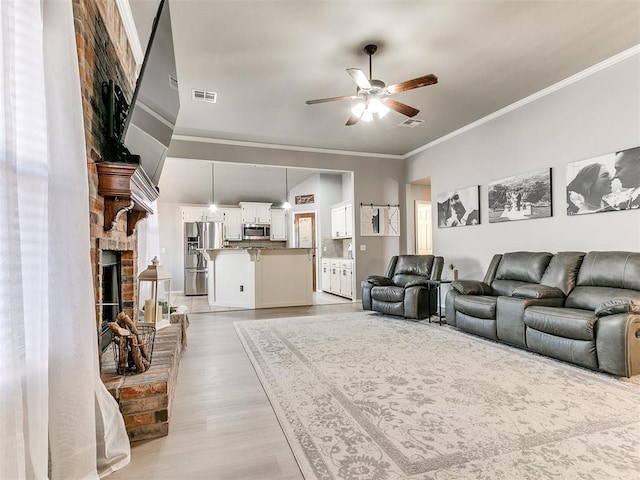 living room with visible vents, a ceiling fan, a fireplace, and crown molding