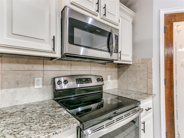 kitchen with stainless steel appliances, light stone countertops, white cabinets, and decorative backsplash