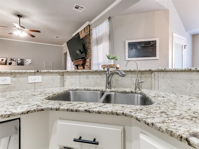 kitchen featuring visible vents, ornamental molding, a sink, light stone counters, and tasteful backsplash