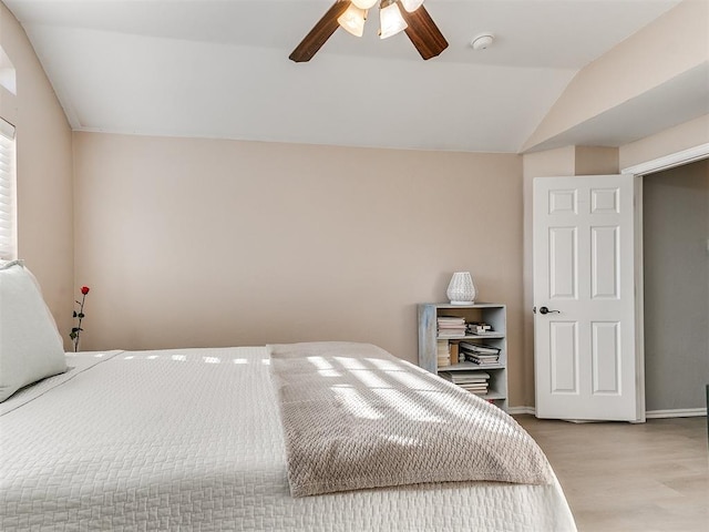 bedroom featuring baseboards, lofted ceiling, wood finished floors, and a ceiling fan