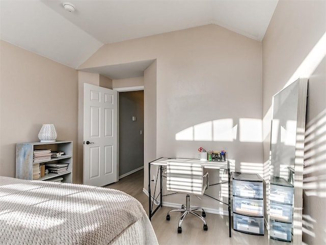 bedroom featuring baseboards, wood finished floors, and vaulted ceiling