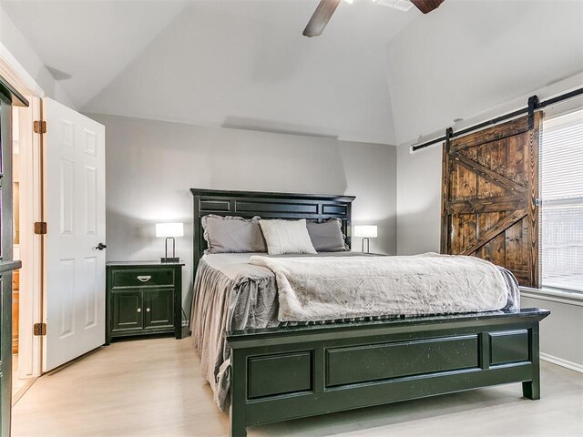 bedroom with lofted ceiling, a barn door, light wood-type flooring, and ceiling fan