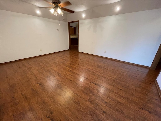 empty room featuring wood finished floors, a ceiling fan, and baseboards