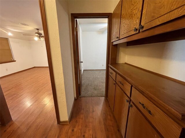 hallway featuring baseboards and dark wood-style flooring