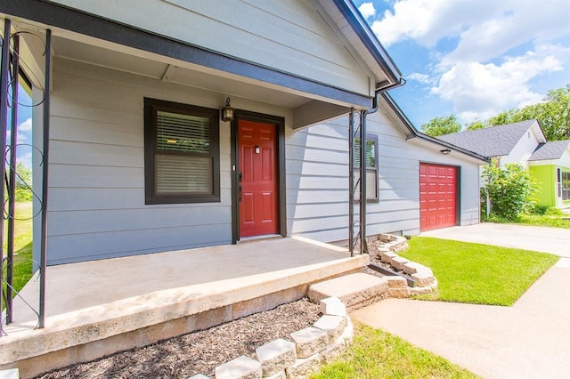 entrance to property with concrete driveway, a porch, and a garage