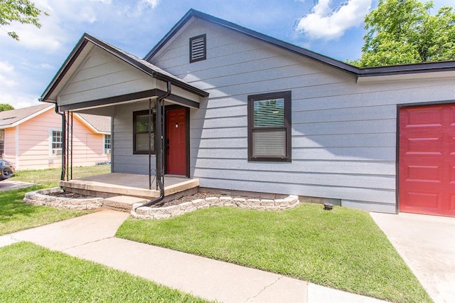 view of front of home featuring a front yard, an attached garage, and covered porch