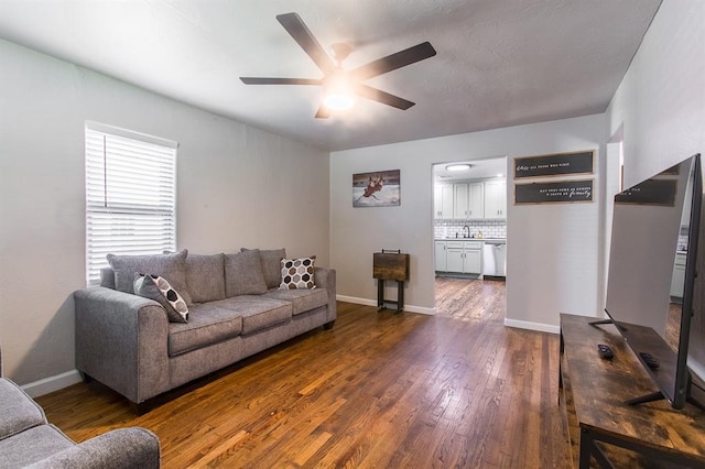 living area with ceiling fan, baseboards, and dark wood-style floors