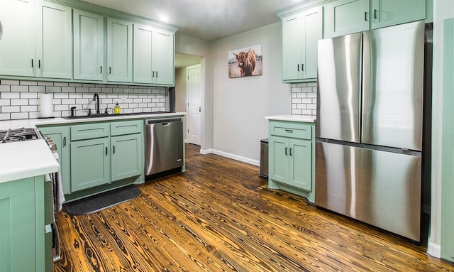 kitchen with green cabinets, dark wood-type flooring, a sink, and stainless steel appliances