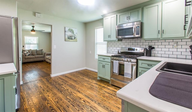 kitchen featuring appliances with stainless steel finishes, light countertops, green cabinets, and dark wood-type flooring