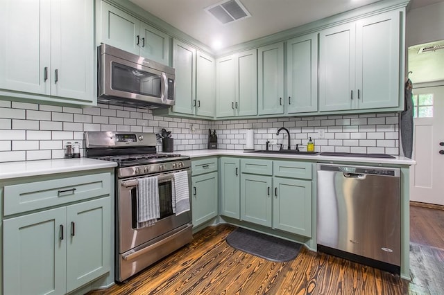 kitchen featuring dark wood finished floors, visible vents, stainless steel appliances, and green cabinets