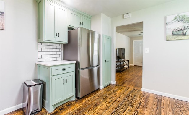 kitchen featuring tasteful backsplash, dark wood finished floors, freestanding refrigerator, light countertops, and green cabinetry