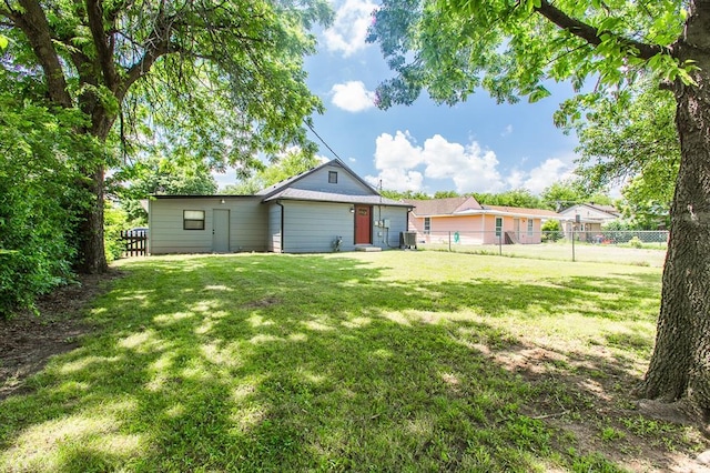 back of house featuring a lawn and fence